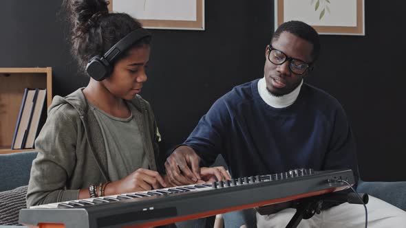 Man Teaching Girl Play Synthesizer