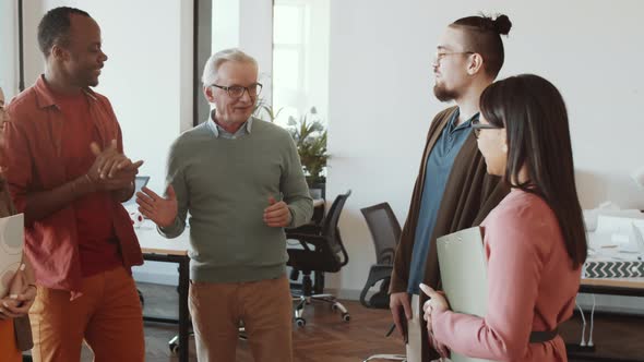 Senior Manager Talking to Cheerful Multiethnic Team in Office