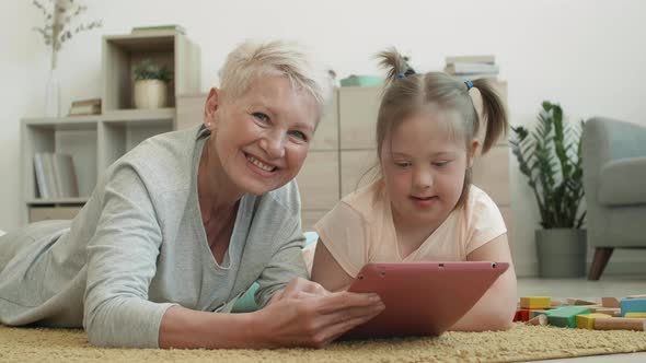 Portrait of Grandmother and Handicapped Girl Using Tablet