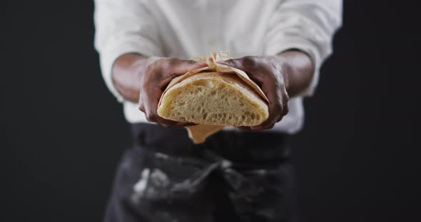 Video of cook holding loaf of bread on black background