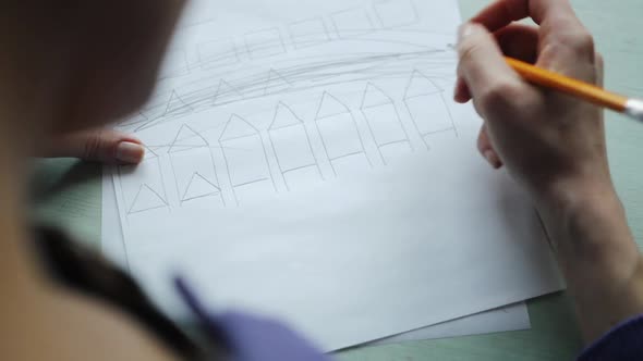 Woman's Hands Drawing on the White Sheet of Paper on the Wood Desk