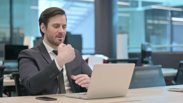 Businessman Having Wrist Pain While Using Laptop in Office