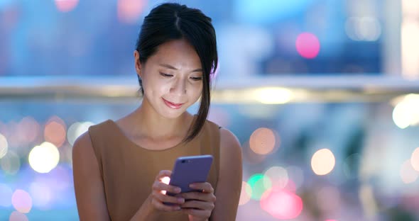 Asian woman check on cellphone in city at night