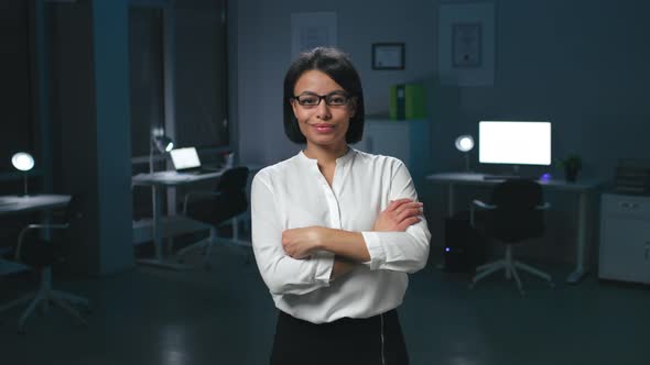 Smiling AfroAmerican Businesswoman Posing at Camera with Arms Crossed in Dark Empty Office