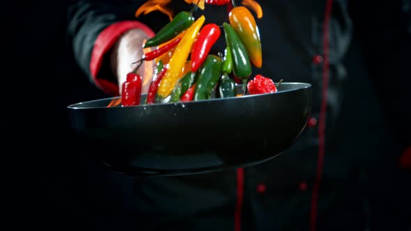 Super Slow Motion Shot of Chef Holding Frying Pan and Falling Chilli Peppers Into Fire at 1000Fps.