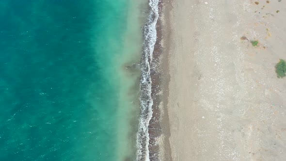 aerial top down view with one half blue tropical ocean and the other half an empty sandy beach with