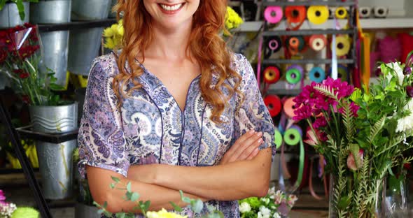 Happy female florist standing with arms crossed in flower shop