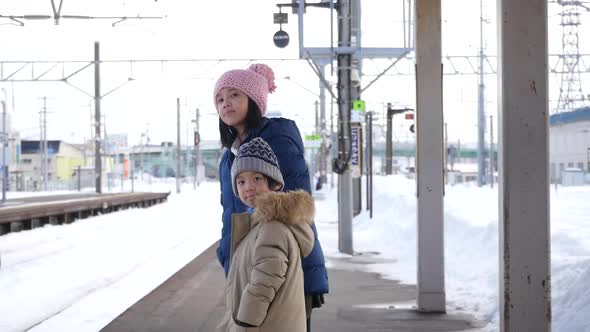 Asian Children Waiting Express Train On Railway Station Platform,Winter Travel Concept 