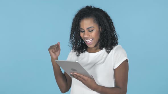 African Girl Excited for Success While Using Tablet Isolated on Blue Background