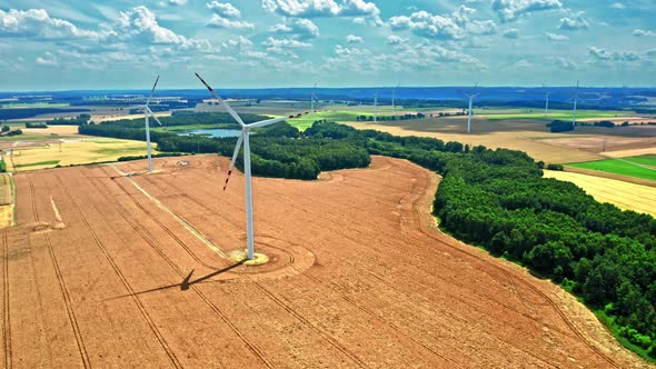 Aerial view of wind turbines on brown field in summer