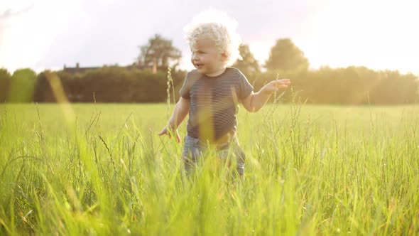 Chubby Baby Boy Gliding His Hands on the Grass Around Him