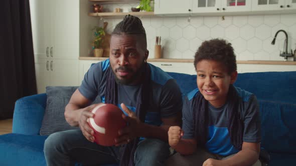 Excited African American Dad and Son with Football Celebrating Scoring Drive