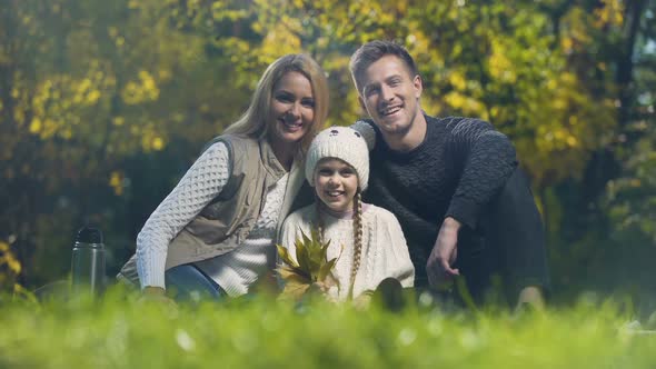 Family Smiling and Showing Thumbs Up on Picnic in Autumn Park