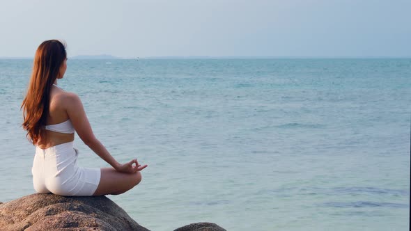 Back of views woman practice yoga lotus pose to meditation summer vacation on pier