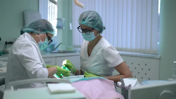 Concentrated Caucasian Dentist and Assistant Checking Teeth of Patient Sitting in Dental Chair