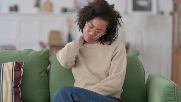 Tired Young African Woman with Neck Pain Sitting on Sofa 