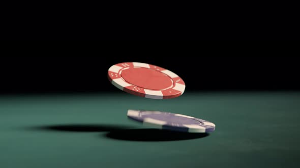 Two casino chips falling on the table. Red and blue tokens on a green table.