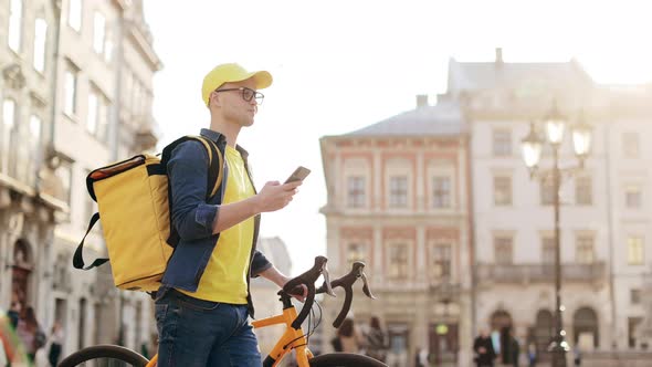 A Happy Delivery Man Who is Going and Texting on a Smartphone