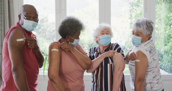 Diverse group of senior friends showing plasters on arms after vaccination against coronavirus