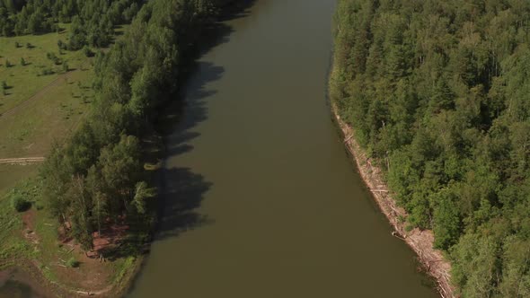 River and Forest, Shot From a Quadcopter. Top View of a Thin River and Fields Around It