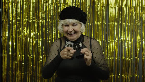 Elderly Style Granny Caucasian Woman in Sunglasses Pointing at Camera on Golden Background