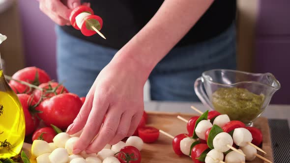 Making Caprese Canapes Sticking Cherry Tomatoes and Mozzarella Cheese Balls on a Skewer