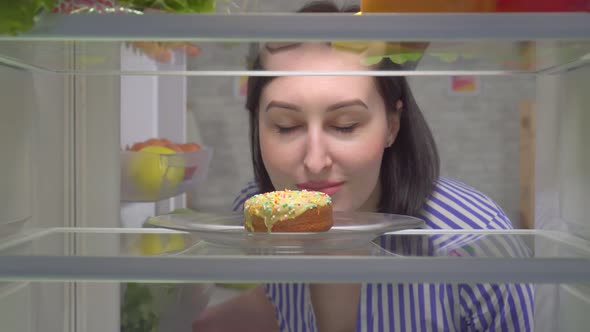 Cute Female Takes a Delicious Doughnut From the Fridge