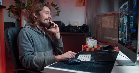 Creative Freelance Man Working at Home Using Computer Receiving Phone Call