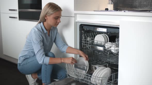 Young Beautiful Woman Unloading Dishes From Dishwasher Machine