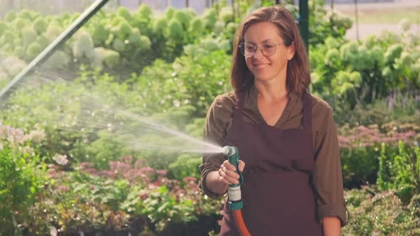 Female Gardener Watering Plants With Hose