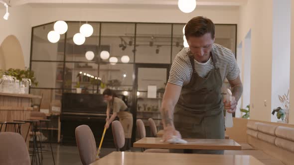 Man Cleaning in Cafe and Smiling