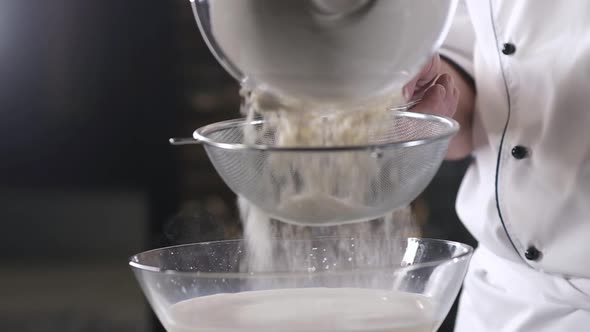 cook in kitchen pours wheat flour into strainer and sifts. Preparing  pasta.