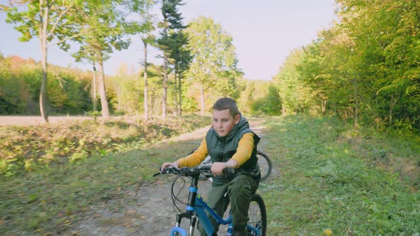 Children Ride Bicycles Near the Forest