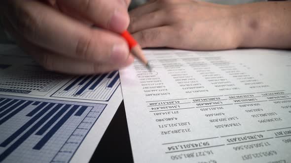 Accountant Analyzing Business Marketing Data on Paper Dashboard at Office Table