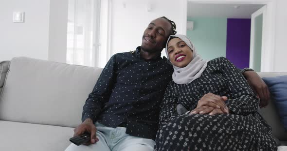 African Couple on Sofa in Modern Apartment Watching Tv