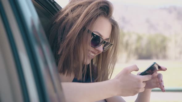 Nice Girl Looks at Phone Sitting in Car at Lawn Slow Motion