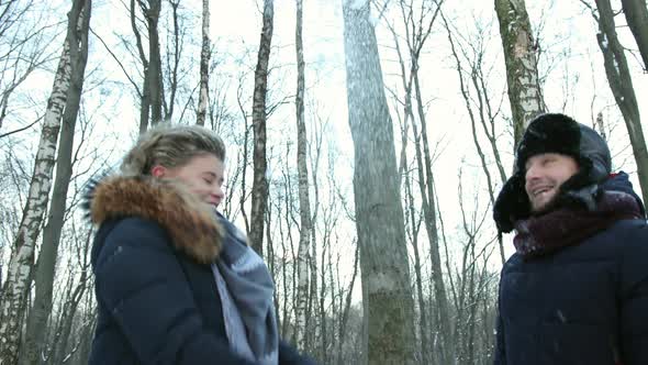 Man and a Woman in Snowcovered Winter Forest Throw Snow at Each Other