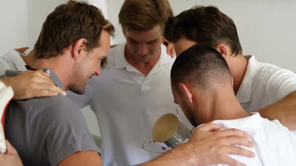 Cricket team forming a huddle in dressing room