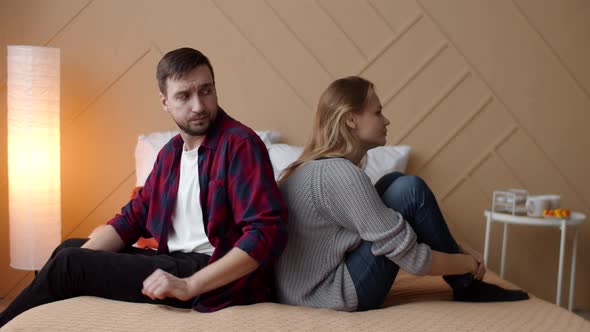 Man and Woman are Sitting on Bed with Their Backs Each Other After an Argument Man Tries to Touch