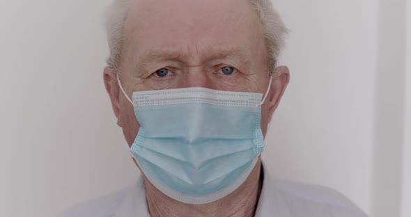 Sad Elderly Man in Medical Mask with Suspected Virus Looking Into Camera