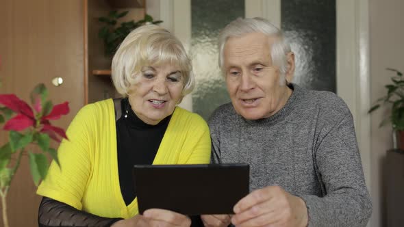 Pretty Mature Senior Couple Grandparents Making Video Call with Tablet at Home