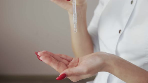 Close Up of Professional Beautician Applying Body Lotion Cream From Pipette on Hands