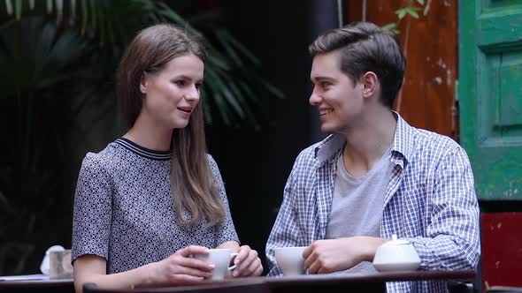 Couple In Cafe. Young People Drinking Coffee And Communicating