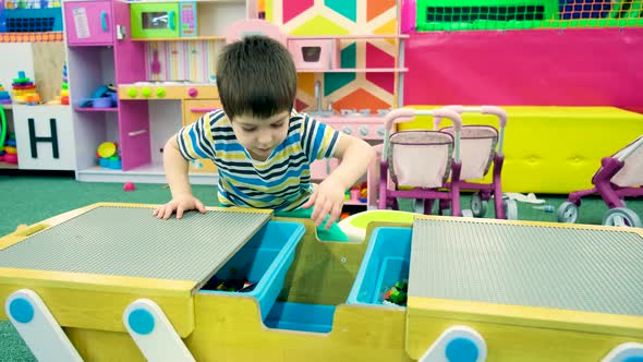 A Preschooler Boy Plays a Construction Set in a Playroom for Children