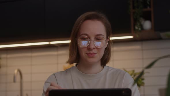 A Girl with Glasses Surfs the Internet in Search of New Things in Online Stores