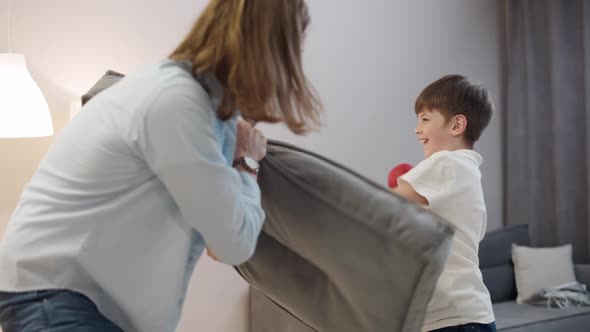 Slow Motion Father and Son Play Boxing a Boy in Red Gloves on His Hands Beats a Sofa Cushion Home