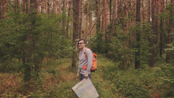 A Traveling Man with Dreadlocks with a Map in the Forest