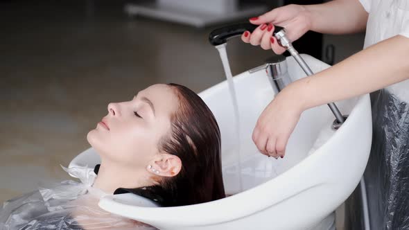 Hairdresser Washing Shampoo Off Client's Head in Beauty Studio