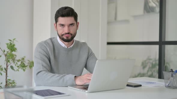 Young Man Shaking Head As No Sign While Using Laptop in Office