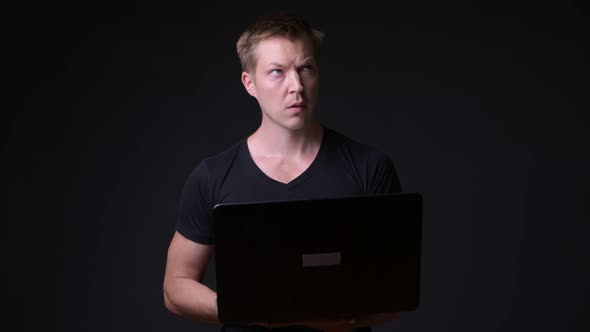 Young Handsome Man with Laptop Against Black Background